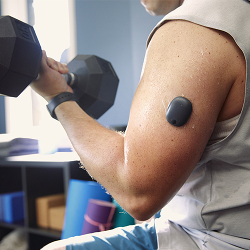 Mann løfter vekter mens han har på seg en langvarig CGM for diabetes.