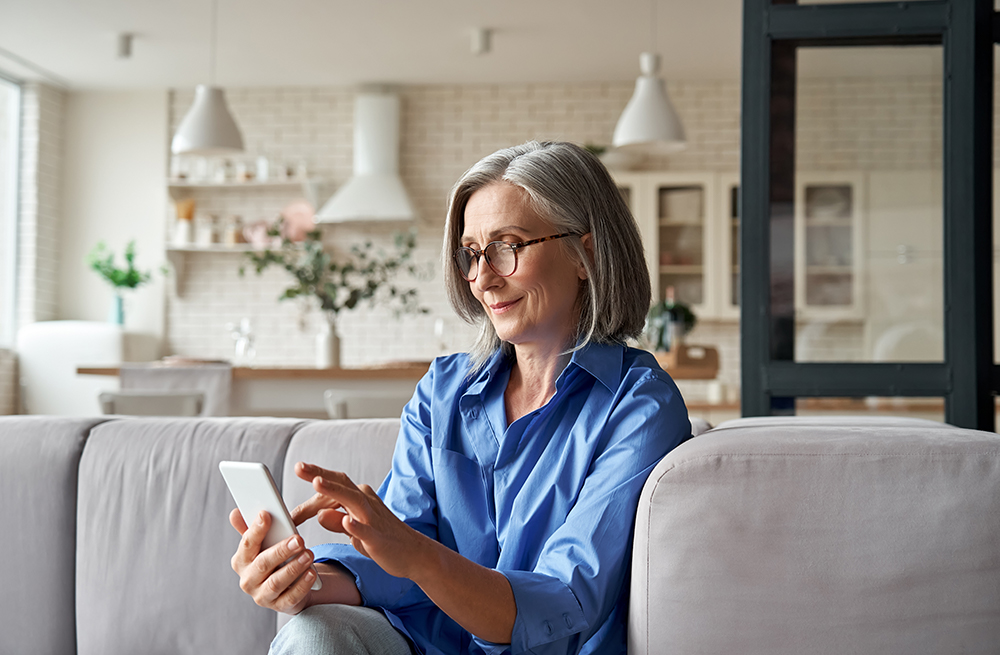Kvinne bruker en mobiltelefon for å lære om kostnaden for Eversense E3 CGM-systemet.