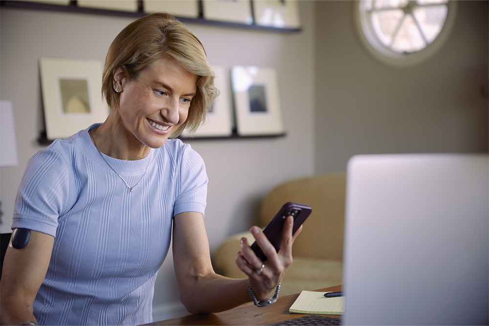 Kvinne bruker telefonen sin til å undersøke forsikringsdekning for implanterbar CGM.
